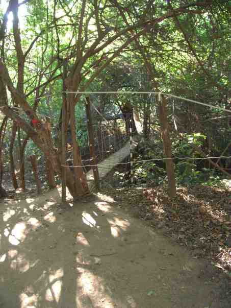 A hanging bridge spans the weir. The red dot on the left of the picture indicates one of the walking paths.